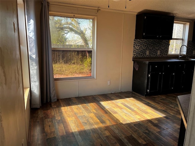 unfurnished dining area with a textured ceiling, dark wood-type flooring, and sink