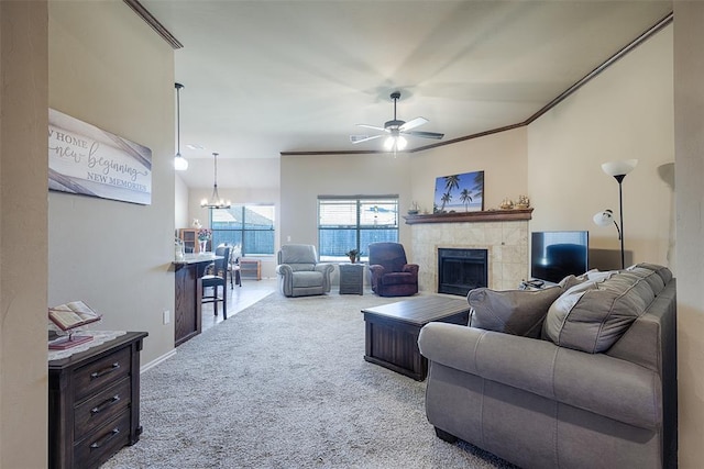 carpeted living room with a fireplace, ceiling fan with notable chandelier, and ornamental molding