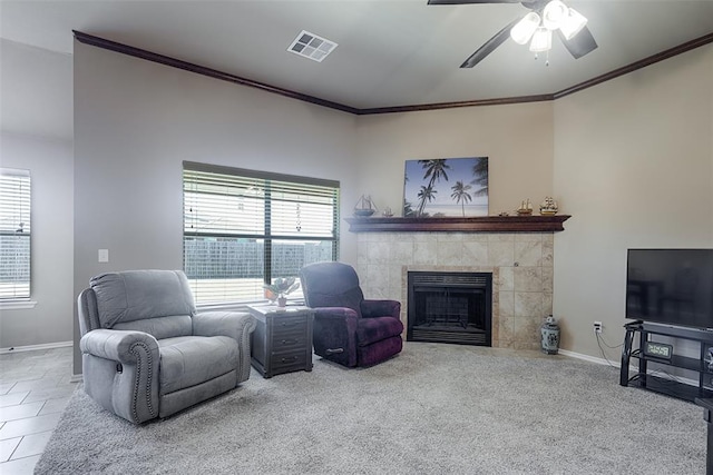 carpeted living room featuring ceiling fan, a tile fireplace, crown molding, and a wealth of natural light