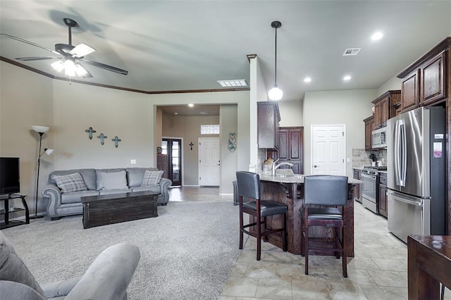 interior space with pendant lighting, crown molding, a breakfast bar area, ceiling fan, and stainless steel appliances