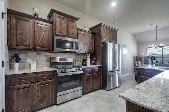 kitchen with an inviting chandelier, stainless steel appliances, vaulted ceiling, and dark brown cabinetry