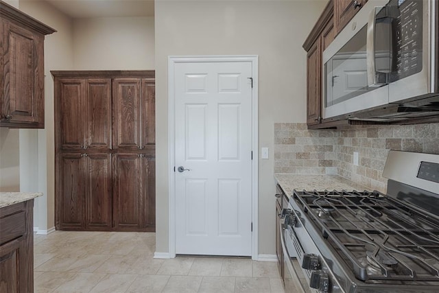 4536 Oasis Ct, Yukon, OK 73099 - kitchen featuring appliances with stainless steel finishes, tasteful backsplash, light stone counters, and baseboards