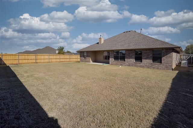 4536 Oasis Ct, Yukon, OK 73099 - rear view of property with a chimney, central air condition unit, brick siding, and a shingled roof