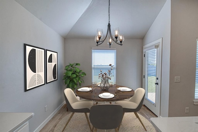 dining space with light hardwood / wood-style flooring, vaulted ceiling, and a notable chandelier