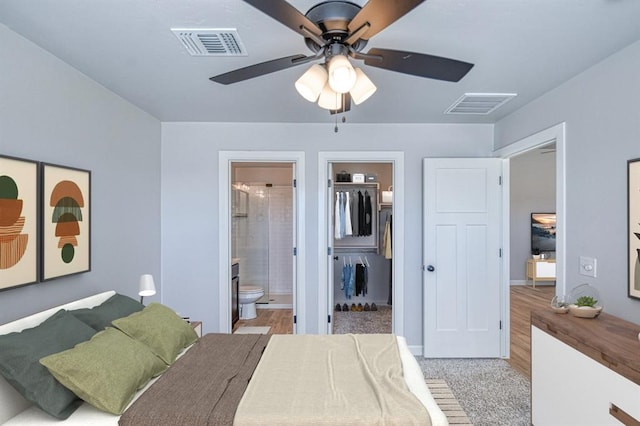 bedroom featuring light hardwood / wood-style flooring, ceiling fan, a spacious closet, connected bathroom, and a closet