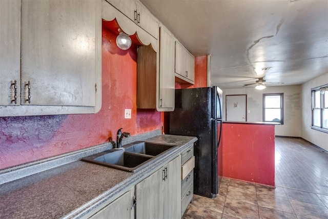 kitchen featuring sink, ceiling fan, black fridge, and light tile patterned flooring