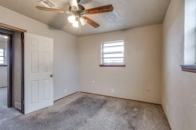 unfurnished room with ceiling fan, light colored carpet, and a textured ceiling