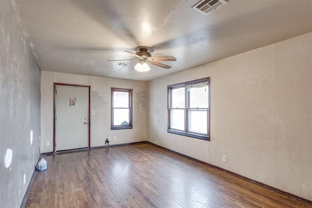 interior space featuring visible vents, ceiling fan, a textured wall, and wood finished floors