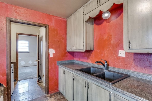 kitchen with a textured wall, a sink, and dark countertops