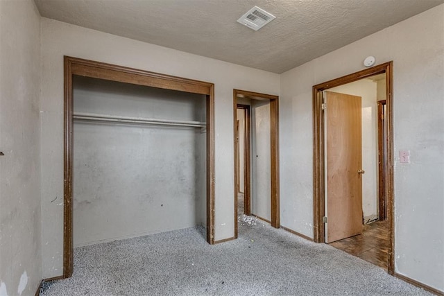 unfurnished bedroom featuring a textured ceiling, a closet, carpet, and visible vents