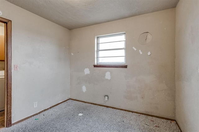 unfurnished room with carpet floors, baseboards, washer / dryer, and a textured ceiling