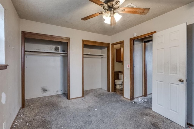 unfurnished bedroom featuring ensuite bathroom, ceiling fan, a textured ceiling, multiple closets, and carpet flooring