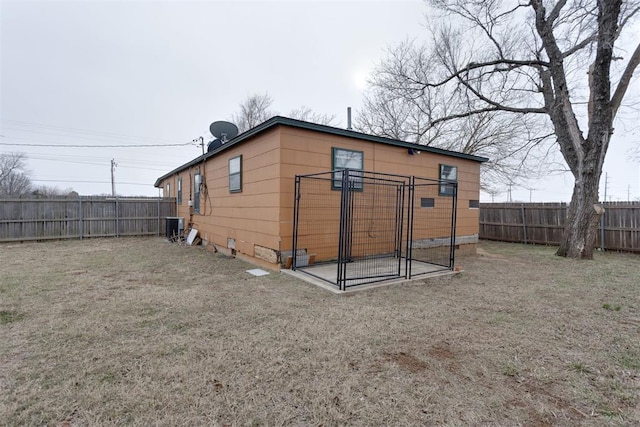 exterior space with central AC, a fenced backyard, and a yard