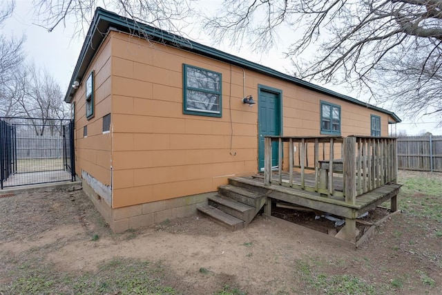 back of property with a deck, fence, and a gate