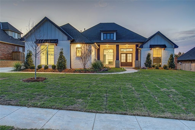 view of front of home with french doors and a lawn