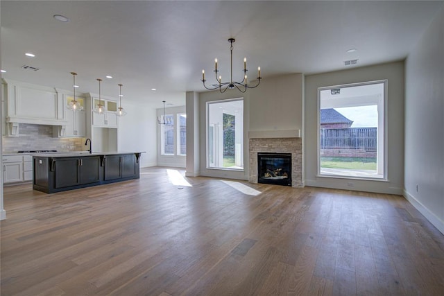 unfurnished living room featuring a fireplace, hardwood / wood-style floors, an inviting chandelier, and sink