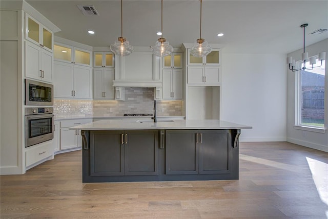 kitchen with pendant lighting, stainless steel appliances, and a kitchen island with sink