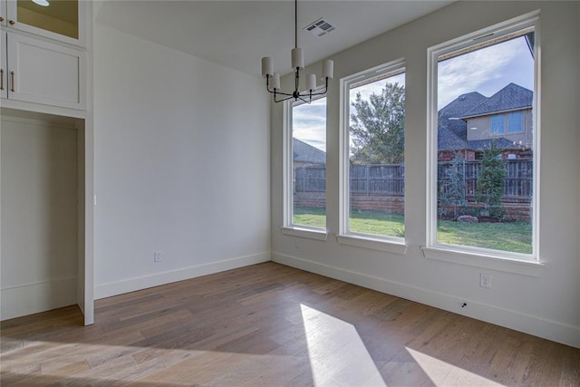 unfurnished dining area featuring a chandelier, a wealth of natural light, and light hardwood / wood-style floors