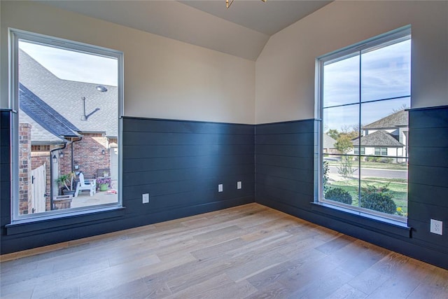 spare room with lofted ceiling and light hardwood / wood-style flooring