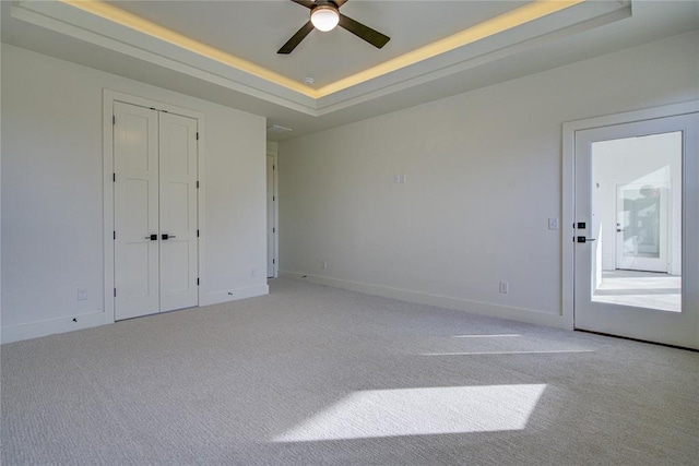 unfurnished bedroom featuring light colored carpet, a raised ceiling, and ceiling fan