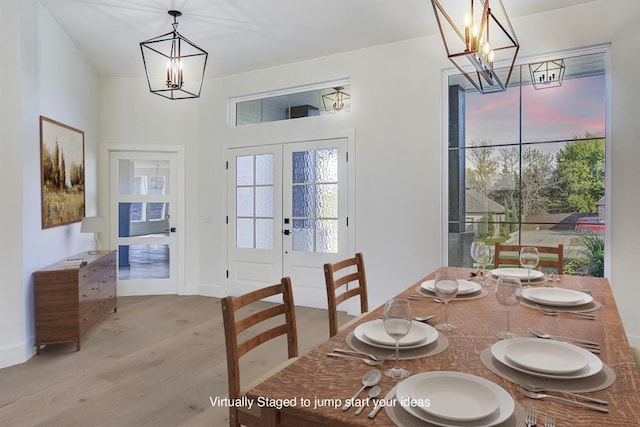 dining space featuring french doors, an inviting chandelier, and light wood-type flooring