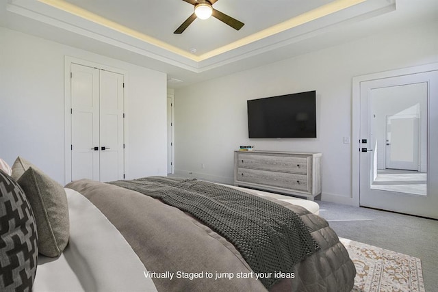 bedroom featuring a raised ceiling, ceiling fan, and light colored carpet