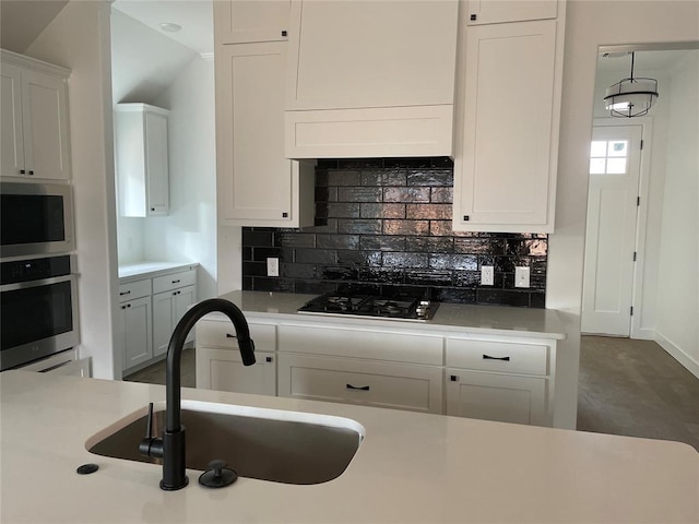 kitchen featuring tasteful backsplash, white cabinetry, sink, and stainless steel microwave