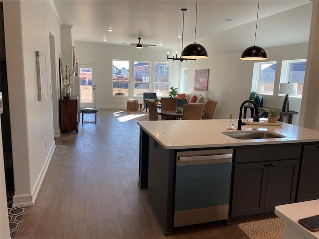 kitchen featuring dishwasher, sink, decorative light fixtures, dark wood-type flooring, and an island with sink