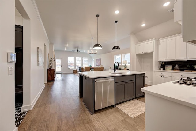 kitchen featuring pendant lighting, sink, stainless steel appliances, an island with sink, and white cabinets