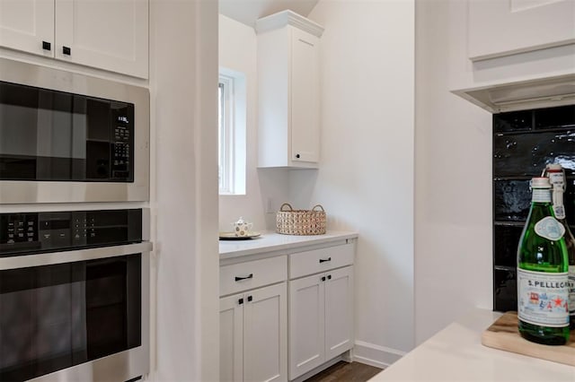 kitchen with built in microwave, a mail area, white cabinetry, dark hardwood / wood-style floors, and oven