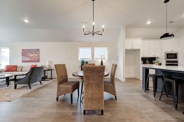 dining room featuring an inviting chandelier, lofted ceiling, a healthy amount of sunlight, and light wood-type flooring