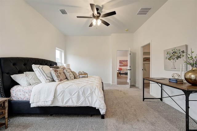 carpeted bedroom featuring a walk in closet and ceiling fan