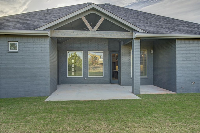 view of exterior entry featuring a patio area and a lawn