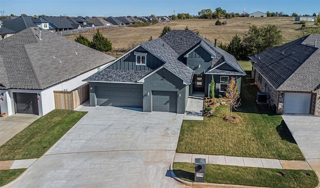 view of front of house featuring a garage, central air condition unit, and a front yard