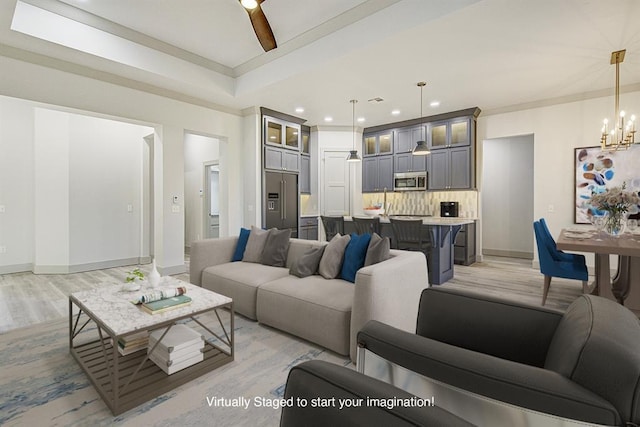 living room with ceiling fan with notable chandelier and light hardwood / wood-style floors