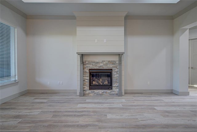 unfurnished living room featuring a fireplace, light wood-type flooring, and ornamental molding