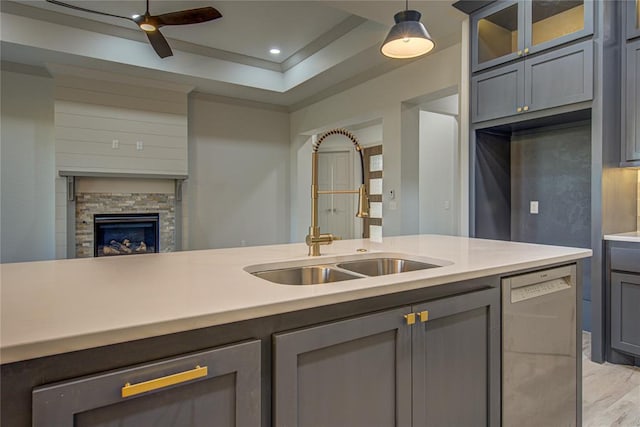 kitchen featuring ceiling fan, sink, stainless steel dishwasher, decorative light fixtures, and a fireplace