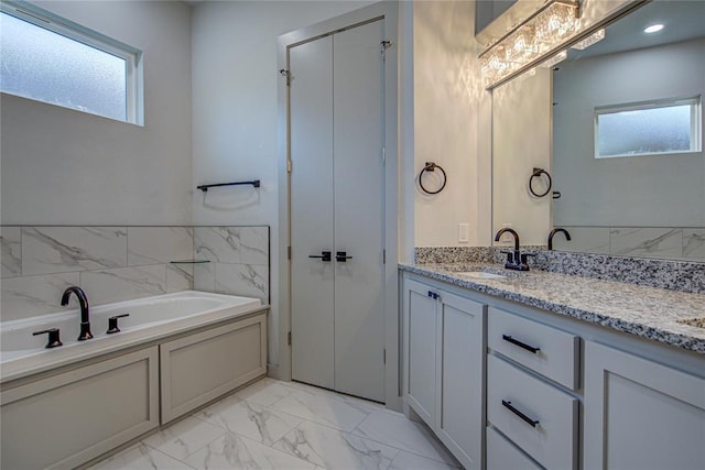 bathroom with plenty of natural light, a tub, and vanity