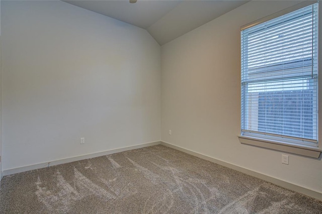 carpeted empty room featuring vaulted ceiling