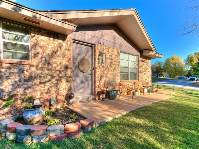 view of exterior entry with a yard