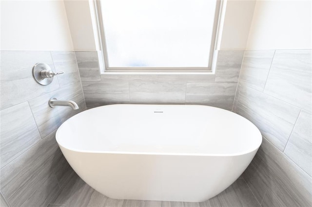 full bathroom with a soaking tub and tile walls