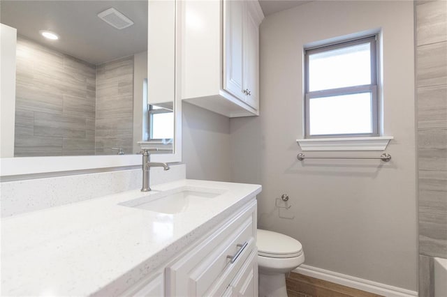 full bath featuring vanity, visible vents, toilet, wood finished floors, and baseboards