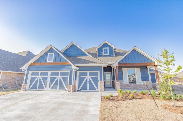 craftsman house with an attached garage, a shingled roof, board and batten siding, and driveway