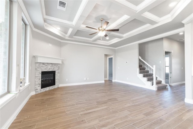 unfurnished living room featuring a glass covered fireplace, a ceiling fan, visible vents, stairway, and coffered ceiling