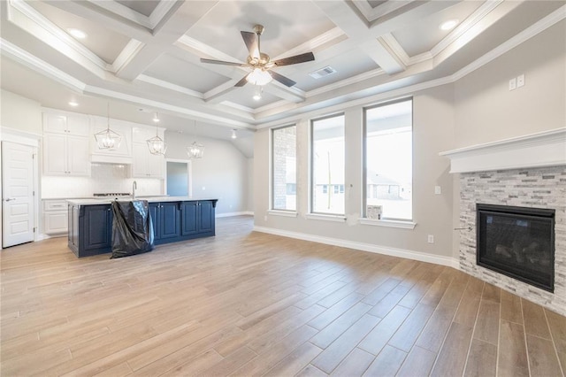 unfurnished living room with visible vents, a ceiling fan, light wood-style floors, beamed ceiling, and a glass covered fireplace