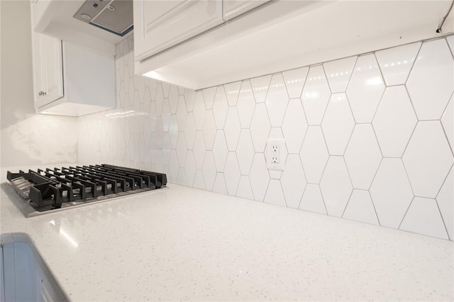 details featuring white cabinets, stainless steel gas stovetop, backsplash, and range hood