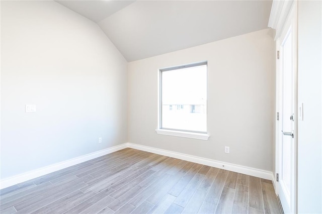 unfurnished room featuring light wood finished floors, baseboards, and lofted ceiling