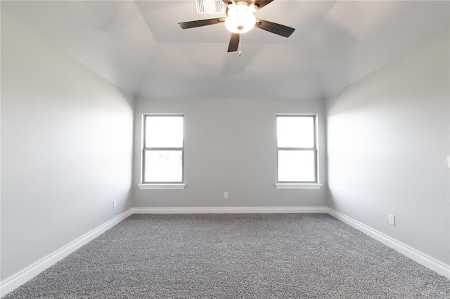 empty room with a wealth of natural light, carpet flooring, vaulted ceiling, and a ceiling fan