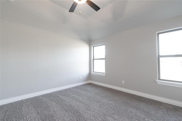 spare room with baseboards, dark carpet, and ceiling fan