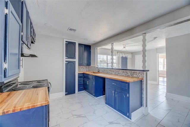 kitchen with wooden counters, backsplash, and plenty of natural light